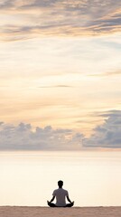 A young woman sits in lotus position on the beach at sunset, her silhouette reflected in the wet sand, evoking peace with the stunning colors of the tranquil ocean horizon