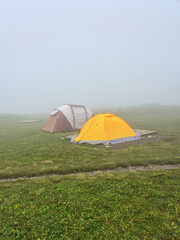 Tent tourist camp on background of the Caucasus mountains in autumn foggy weather