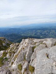 Fototapeta premium Standing on a rocky mountain peak with a view of distant mountains and valleys below