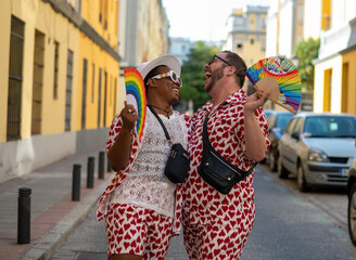 Gay couple with a hand fan with the colors of the LGTBI flag