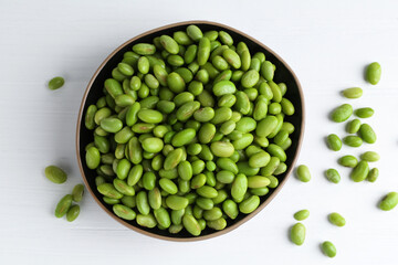 Fresh edamame soybeans in bowl on white wooden table, top view