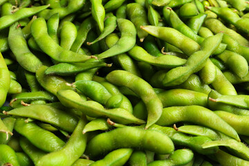 Fresh edamame pods as background, closeup view