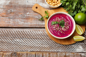 Tasty beetroot hummus in bowl and products on wooden table, flat lay. Space for text