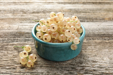 Fresh white currant berries in bowl on wooden table