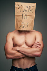 Studio, person and face with paper bag for hide, insecure and criticism of beauty standards with...