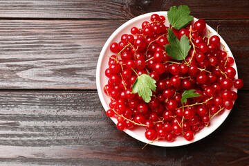 Fresh red currants and leaves on wooden table, top view. Space for text