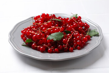 Fresh red currants and leaves on white table, closeup