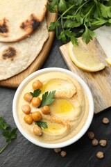 Delicious hummus with olive oil and chickpeas served on grey textured table, flat lay