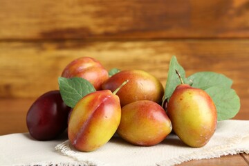 Ripe plums and leaves on table, closeup