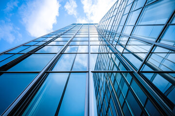 Obraz premium Glass facade skyscraper reflecting the blue sky and clouds.