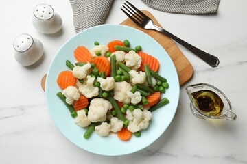 Tasty cooked cauliflower with green peas, string beans and carrot slices served on white marble...