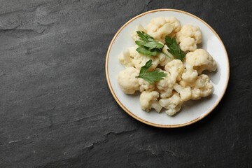 Tasty cauliflower with parsley on black table, top view. Space for text