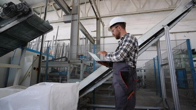 Windows factory chief engineer is using a laptop with an engineering software on production line