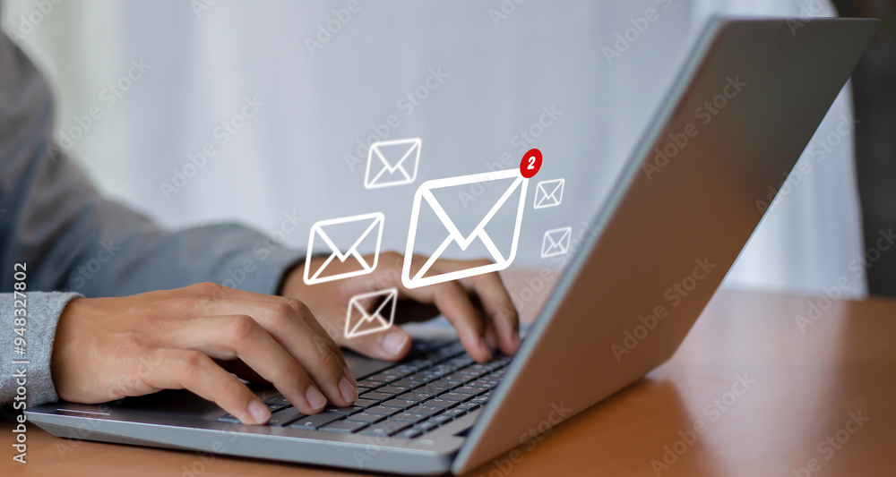 Wall mural man uses laptop with notification icon of two new email messages. communication business technology.