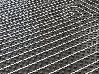 A detailed image of a radiant floor heating system being installed, showing pipes, insulation, and layout.
