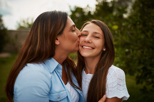 Kiss, mom and daughter in park for portrait, love or bonding together for single parent or care. Outdoor, relax and proud mother in nature for support, girl or teenager with smile, growth or newborn