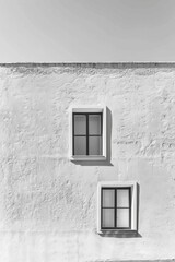 A minimalist white wall featuring beautifully symmetrical windows creates a serene view