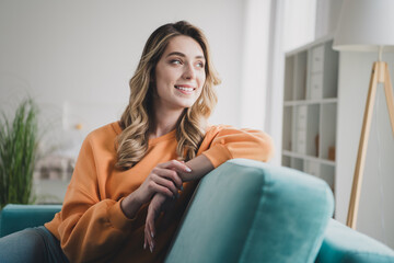 Photo portrait of nice cheerful girl sit sofa look window dreamy dressed orange garment spend pastime spacious house indoors room
