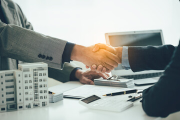 A condo sales representative shakes hands with a client to come to an agreement on the real estate...