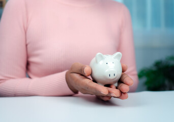 Close-Up Woman Hand holding a piggy bank for saving money and financial concept, Business Banking and Financial Concept. Saving money for retirement funds and insurance concept.