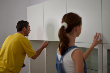 Obraz premium A father and a daughter are working together to install new cabinets
