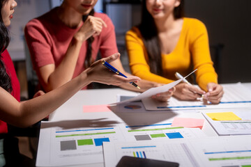 Marketing team working late analyzing financial charts and graphs