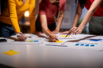 Fototapeta premium Business team working late analyzing financial charts using sticky notes