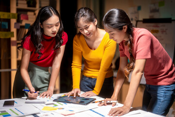 Three asian businesswomen working together using a digital tablet during a late night meeting