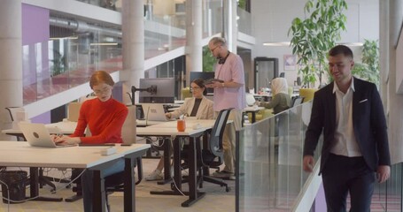 A director arrives at a large, modern office, where he joins his colleagues, exemplifying corporate leadership and teamwork in a dynamic workplace