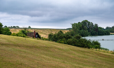Fototapeta premium Green meadows and a water pond at the Danish countryside around Ugledige, Denmark