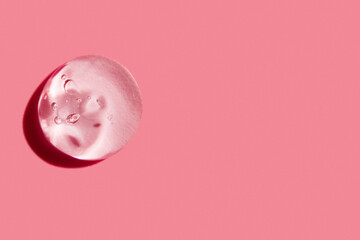 smear of clear gel on pink background with empty space.