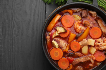 Tasty homemade stew with vegetables on grey wooden table, top view. Space for text