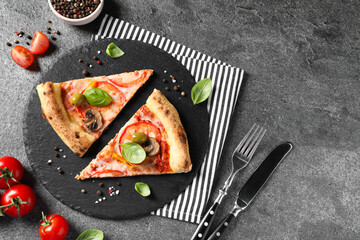 Cut delicious vegetarian pizza, cutlery and ingredients on grey table, top view. Space for text
