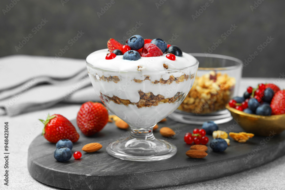 Poster Tasty yogurt with fresh berries, granola and nuts on gray table, closeup