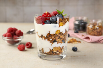 Tasty yogurt with fresh berries, granola and mint in glass on gray textured table