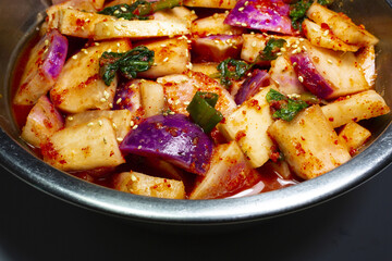 Close-up of Korean Food Turnip Kimchi with green onion and chili powder on stainless basin, South Korea