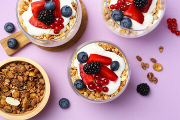 Tasty yogurt with fresh berries and granola in glasses on violet background, flat lay