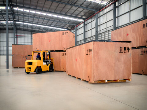 Project cargo in big wooden boxes stored in the warehouse. The cargo in wooden boxes handling by forklift.