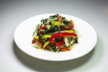 Close-up of Korean Food Seasoned Green Laver with red and yellow paprika on white round plate, South Korea