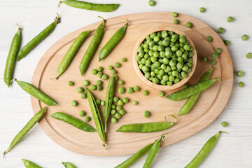Fresh green peas and pods on white wooden table, flat lay