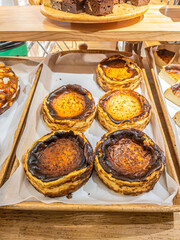 Famous San Sebastian cheesecake displayed on a traditional Basque bakery counter. Whole cake with a caramelized top and the portions showcasing its iconic creamy interior texture.