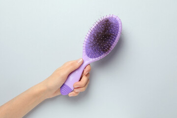 Woman with brush and lost hair on grey background, top view. Alopecia problem