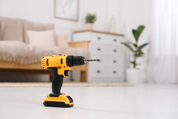 Cordless electric screwdriver on floor at home. Space for text