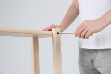 Woman with screwdriver assembling furniture indoors, closeup