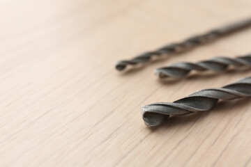 Different drill bits on wooden surface, closeup. Space for text