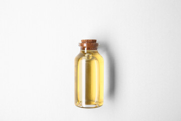 Essential oils in bottle on light background, top view