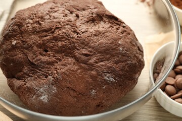 Chocolate dough in bowl on wooden table, closeup