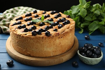 Delicious homemade blueberry pie with mint and fresh berries on blue wooden table, closeup