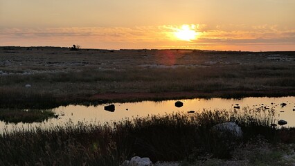 Partially cloudy sunset above salty marsh pond and rocky landscape near coastline of Adriatic sea, location north of Razanac town, Zadar district.