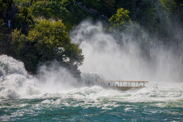 Obraz premium a boat between the roaring rhine waterfall with high waves and lots of spray